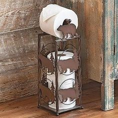 an iron rack holding two rolls of toilet paper and a tissue dispenser