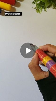 a person holding a pen in their left hand and writing on it with crayons