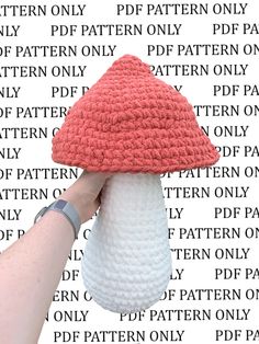 a crocheted red and white hat is held up by a woman's hand