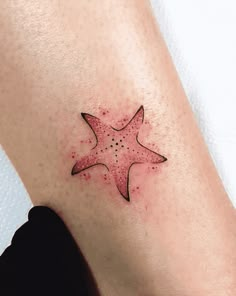 a small starfish tattoo on the right arm and leg, it is pink with black dots