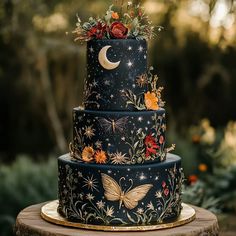 a three tiered cake decorated with flowers and butterflies on a wooden table in front of trees