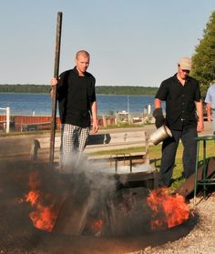 two men standing next to an open fire pit