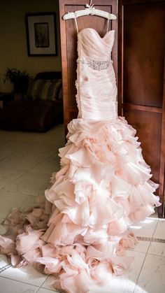 a dress hanging on a hanger in front of a door with the bride's gown