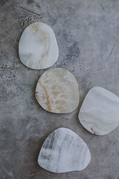 three pieces of marble sitting on top of a cement floor