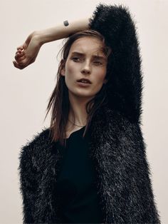 a woman is holding her hair in the air and wearing a furry coat over her head