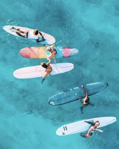 three people on surfboards in the water with one person standing up and another laying down