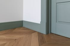 an empty room with wood flooring and green painted walls, next to a door