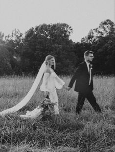 a bride and groom walking through the grass