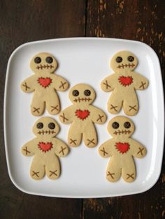 cookies decorated to look like zombies on a white plate with red heart in the middle