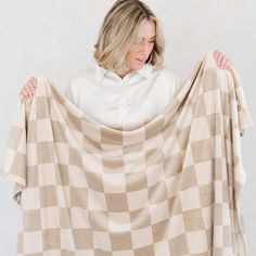 a woman is holding up a checkered blanket