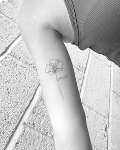 a woman's arm with a single flower tattoo on the left side of her arm