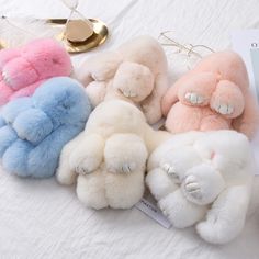 four small stuffed animals sitting on top of a white bed next to a pair of eye glasses