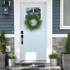 the front door is decorated with wreaths and potted plants