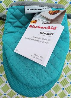 the kitchen aid mini mitt has been placed on top of a green and white blanket