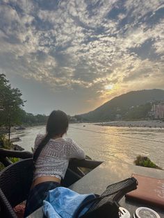 a woman sitting at a table looking out over the water