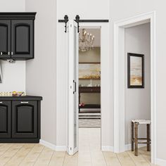 an open door leading to a kitchen with black cabinets and white walls, along with a chandelier hanging from the ceiling