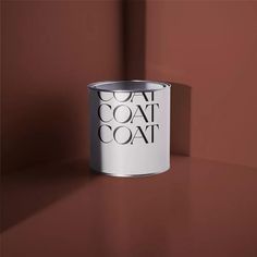 a white paint can sitting on top of a brown table next to a red wall