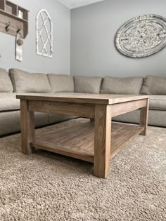 a wooden coffee table sitting on top of a carpeted floor next to a couch