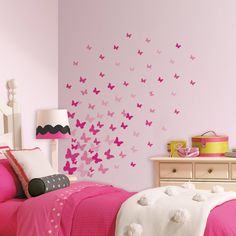 a bedroom with pink walls and butterflies on the wall above the bed, along with a lamp