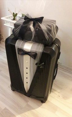 a black suitcase with a bow on it and some presents wrapped around the top one