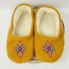 a pair of yellow slippers sitting on top of a wooden floor next to a white wall