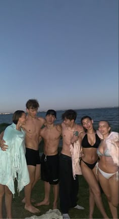 a group of young people standing next to each other near the ocean at night time