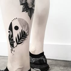 a woman's leg with a tattoo on it that has an image of a face and leaves