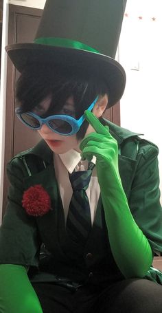 a man dressed in green and black with blue glasses