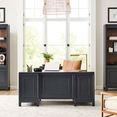 a living room scene with focus on the desk and bookshelf in the background