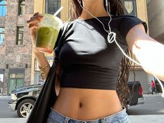 a woman with headphones on holding a drink in her hand and listening to music