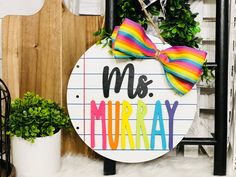 a wooden sign with a bow on it that says ms and mrs murray next to a potted plant