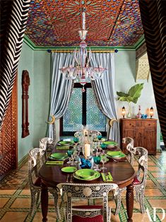 the dining room is decorated in green and blue colors with an intricate ceiling design above it