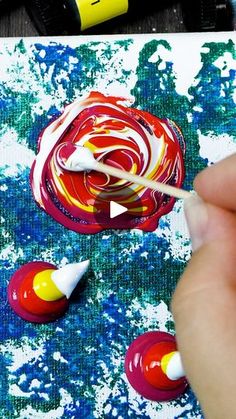 someone is painting something red, yellow and white with acrylic paint on it