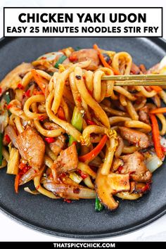 chicken yaki udon with noodles and vegetables in a black plate on a white table