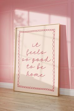 a pink room with a framed sign that says it feels so good to be home