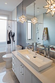 a bathroom with two lights hanging from the ceiling and a large mirror on the wall