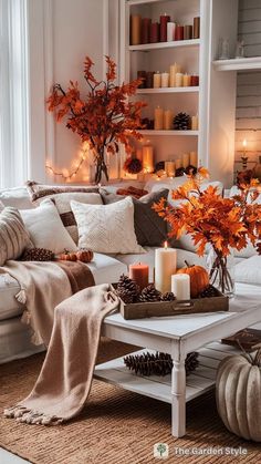 a living room filled with white furniture and lots of fall decorations on the coffee table