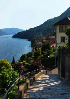 the steps lead down to the water and houses on the hill side with mountains in the background