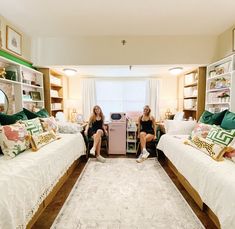 two women sitting on twin beds in a room with bookshelves and rugs