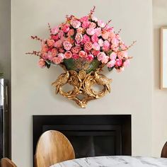 there is a vase with pink flowers in it on the wall above a fireplace mantel