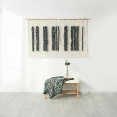 a white room with two wall hangings on the wall and a small table in front of it