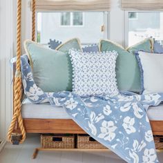 a bed with blue and white pillows on it's headboard in front of a window