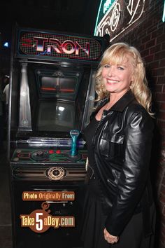 a woman standing in front of an old fashioned video game with neon signs on it