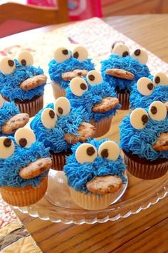 cupcakes with blue frosting and googly eyes are on a clear plate