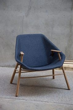 a blue chair sitting on top of a cement floor next to a wall with a wooden frame