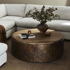 a living room with a round coffee table and couches in the background, including a white sectional sofa