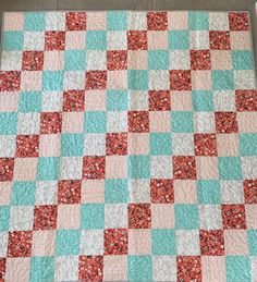 a blue and pink quilt is laying on the floor