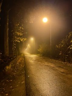 an empty street at night with no cars on it and the lights turned on in the distance