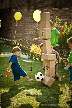 some kids are playing with a soccer ball in the yard while others watch from behind