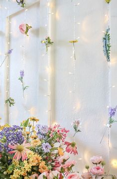 flowers and lights hanging from the side of a wall